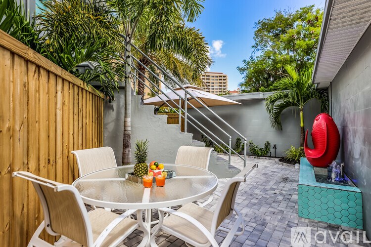 A patio with a glass table surrounded by chairs and a red sculpture.
