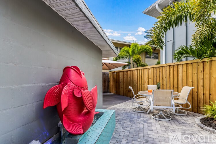 A red fish statue is sitting on a brick patio.