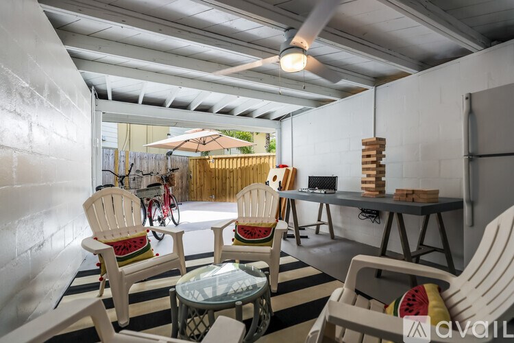 A patio with white chairs and a glass table.