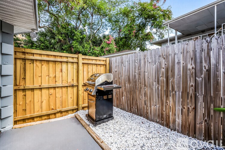 A backyard with a grill and a wooden fence.