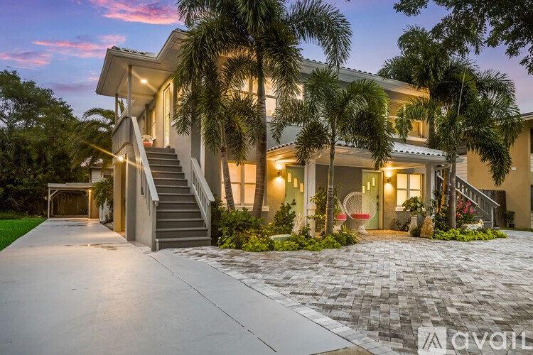 A modern house with a driveway and palm trees in front.