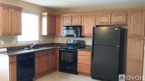 A kitchen with wooden cabinets and black appliances.