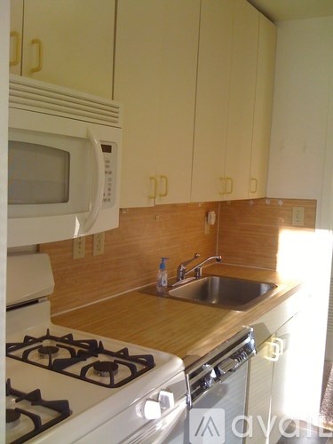 A kitchen with a white stove and a white microwave above the stove.