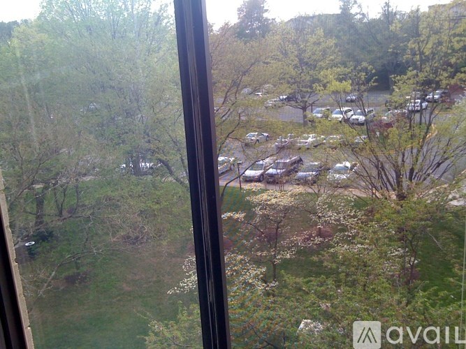 A view from a window looking out at a parking lot and trees.
