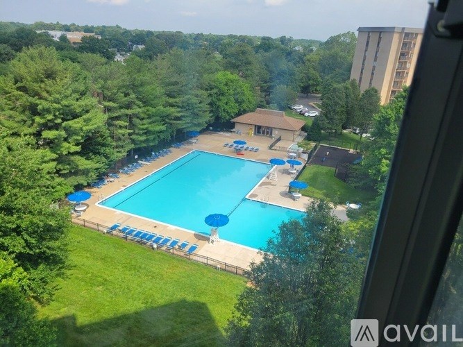 A large swimming pool surrounded by trees and a building in the background.