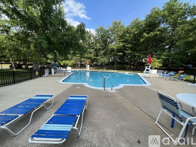 A pool with sun loungers and trees in the background.