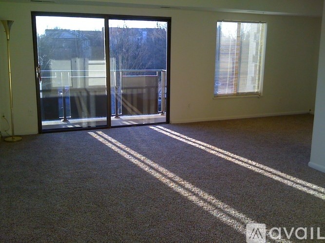 A room with a carpeted floor and a large window with blinds.