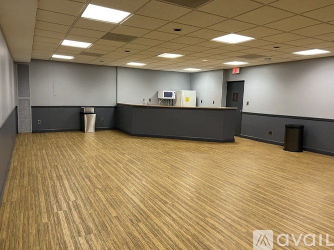 A spacious room with wooden flooring and a reception desk.