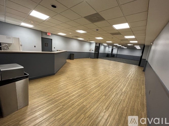 A spacious office room with wood flooring and a reception desk.