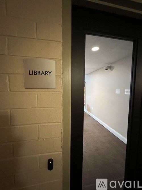 A white sign on a brick wall that says library.