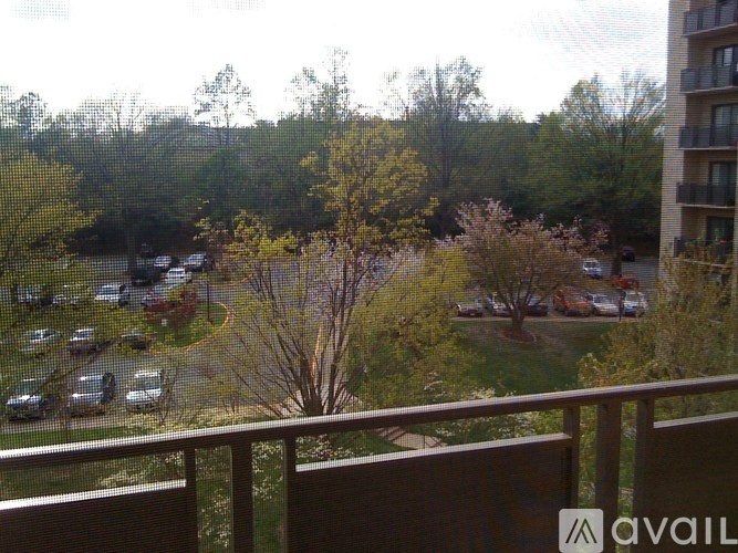 A view from a balcony overlooking a parking lot and trees.