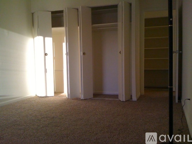 A carpeted room with a wall of windows and a door.