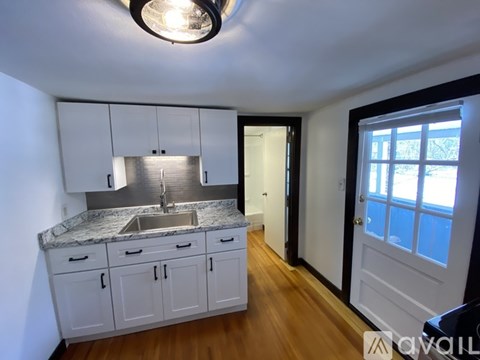 A kitchen with white cabinets and a marble countertop.