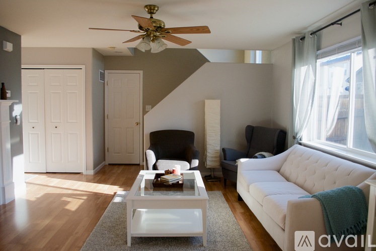 A living room with a white couch, a coffee table, and a ceiling fan.