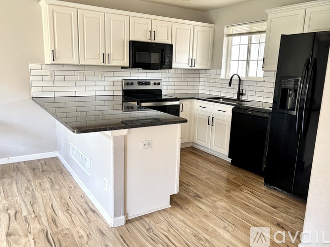 A kitchen with wooden cabinets and a black refrigerator.