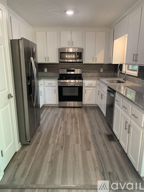 A kitchen with white cabinets and a wooden floor.