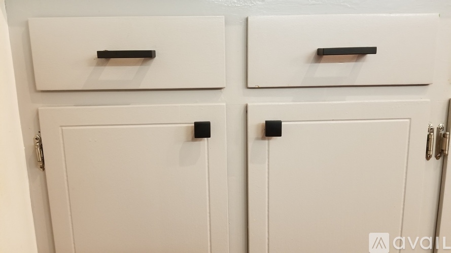 Two white cupboards with black handles and locks.