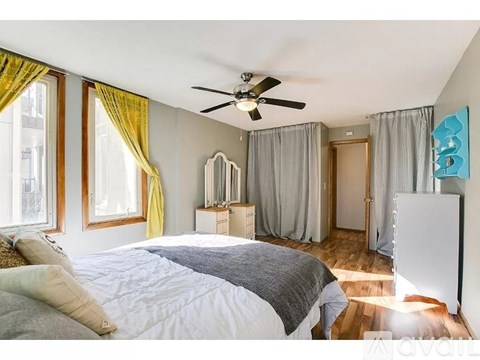 A bedroom with a large bed and a ceiling fan.