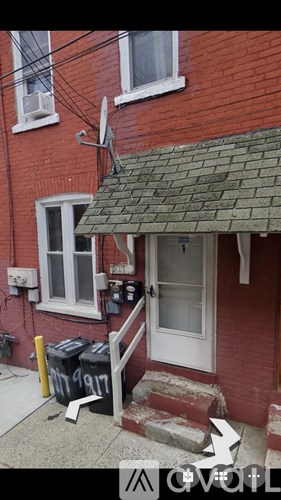 A red brick house with a white door and a broken window.