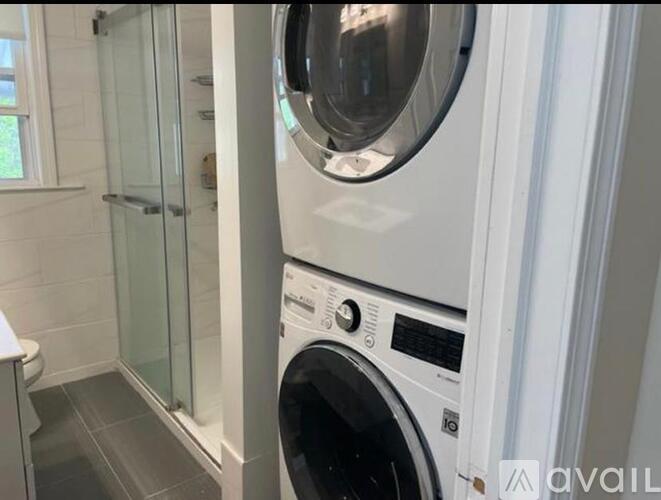 A washing machine is in a bathroom next to a glass shower door.