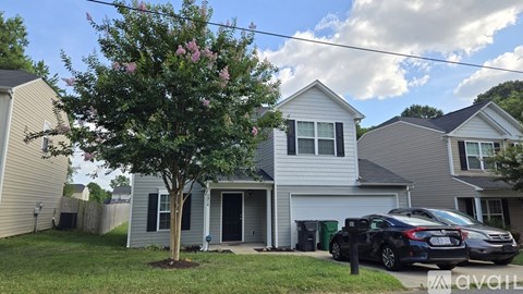 A house with a tree in front and a car parked in the driveway.