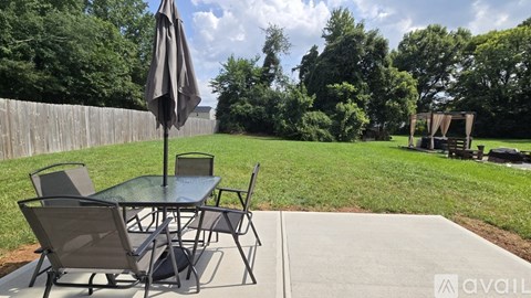 A patio table with chairs and an umbrella is set up on a concrete slab.