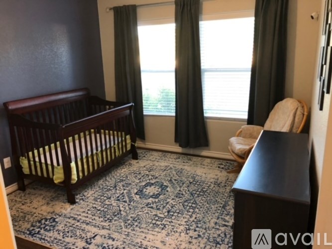A baby's room with a crib, a chair, and a rug.