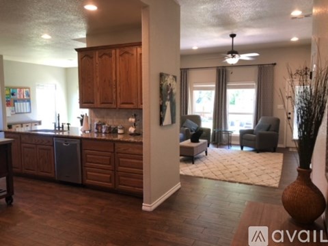 A kitchen with wooden cabinets and a dining area with grey chairs.
