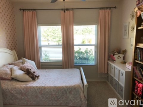A bedroom with a bed, a window with curtains, and a ceiling fan.