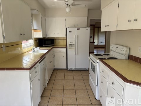 A kitchen with white appliances and cabinets.