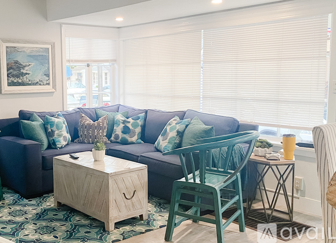A living room with a blue couch, a wooden coffee table, and a green chair.