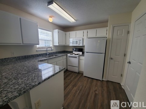 A kitchen with white cabinets and a granite countertop.