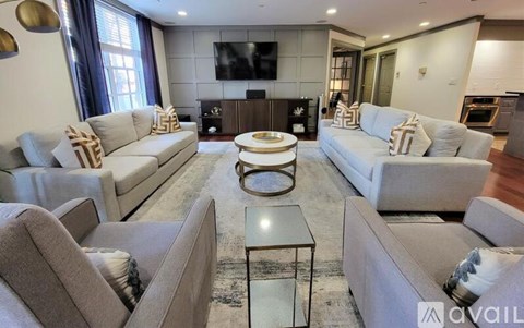 A modern living room with grey couches and a glass coffee table.