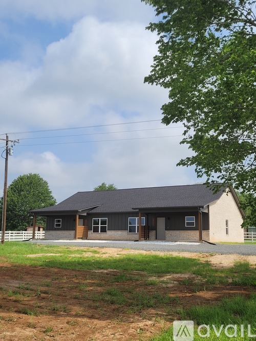 A house with a grey roof and a white fence in front of it.