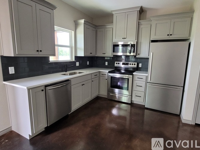 A kitchen with brown flooring and white walls.