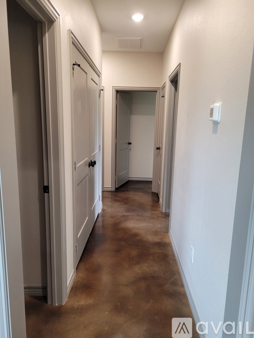 A long hallway with white walls and brown floors.