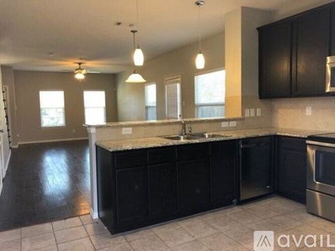 A kitchen with black cabinets and a marble countertop.