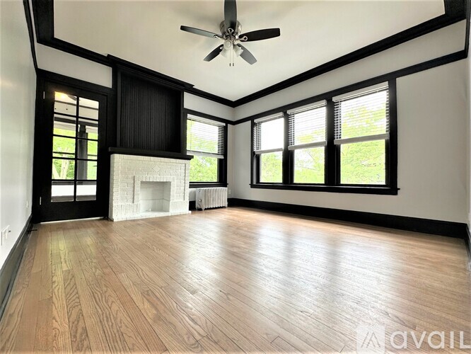 A spacious room with wood flooring and a ceiling fan.