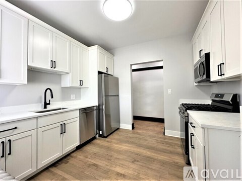A kitchen with white cabinets and a stainless steel refrigerator.