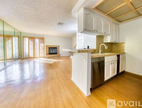 A kitchen with wooden floors and white cabinets is available for rent.