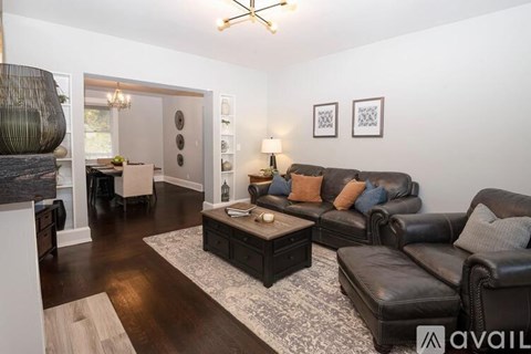 A living room with a black leather couch and a coffee table.