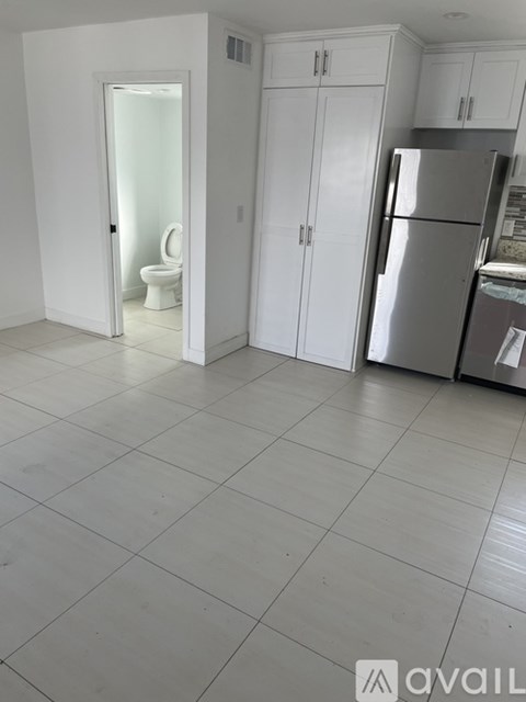 A kitchen with white cabinets and a silver refrigerator.