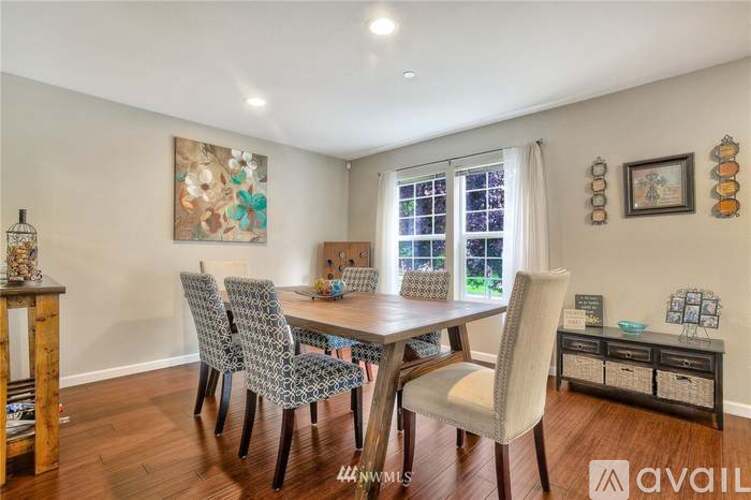 A dining room with a table set for four and a painting on the wall.