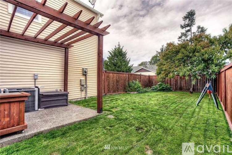 A backyard with a wooden pergola and a hot tub.