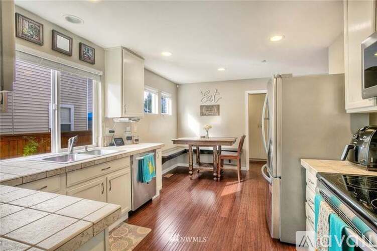 A kitchen with wooden floors and a refrigerator on the right.