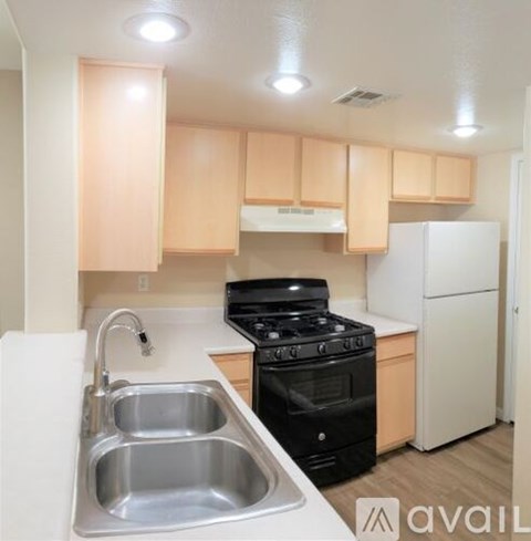 A kitchen with a black stove top oven and a white refrigerator.