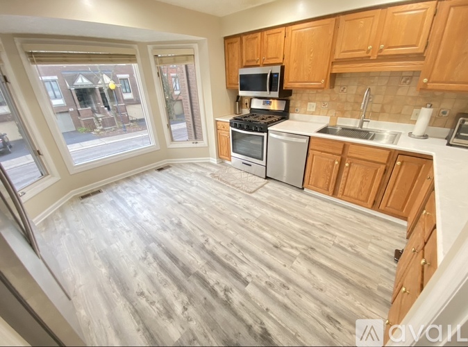 A kitchen with wooden cabinets and a grey floor.