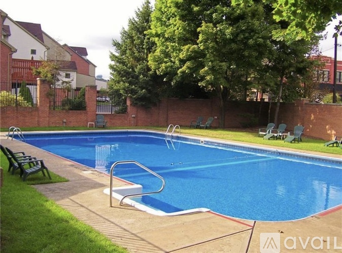 A small pool with a red brick wall and a green lawn.