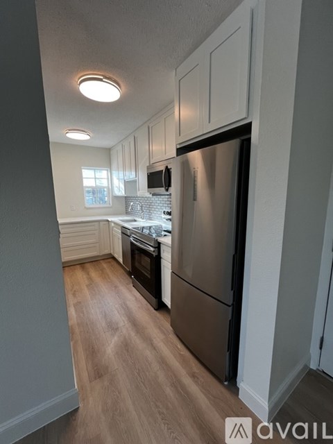 A kitchen with a stainless steel refrigerator and wooden flooring.