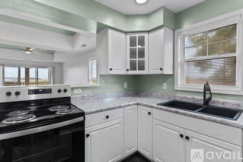 A kitchen with a black stove top oven and white cabinets.